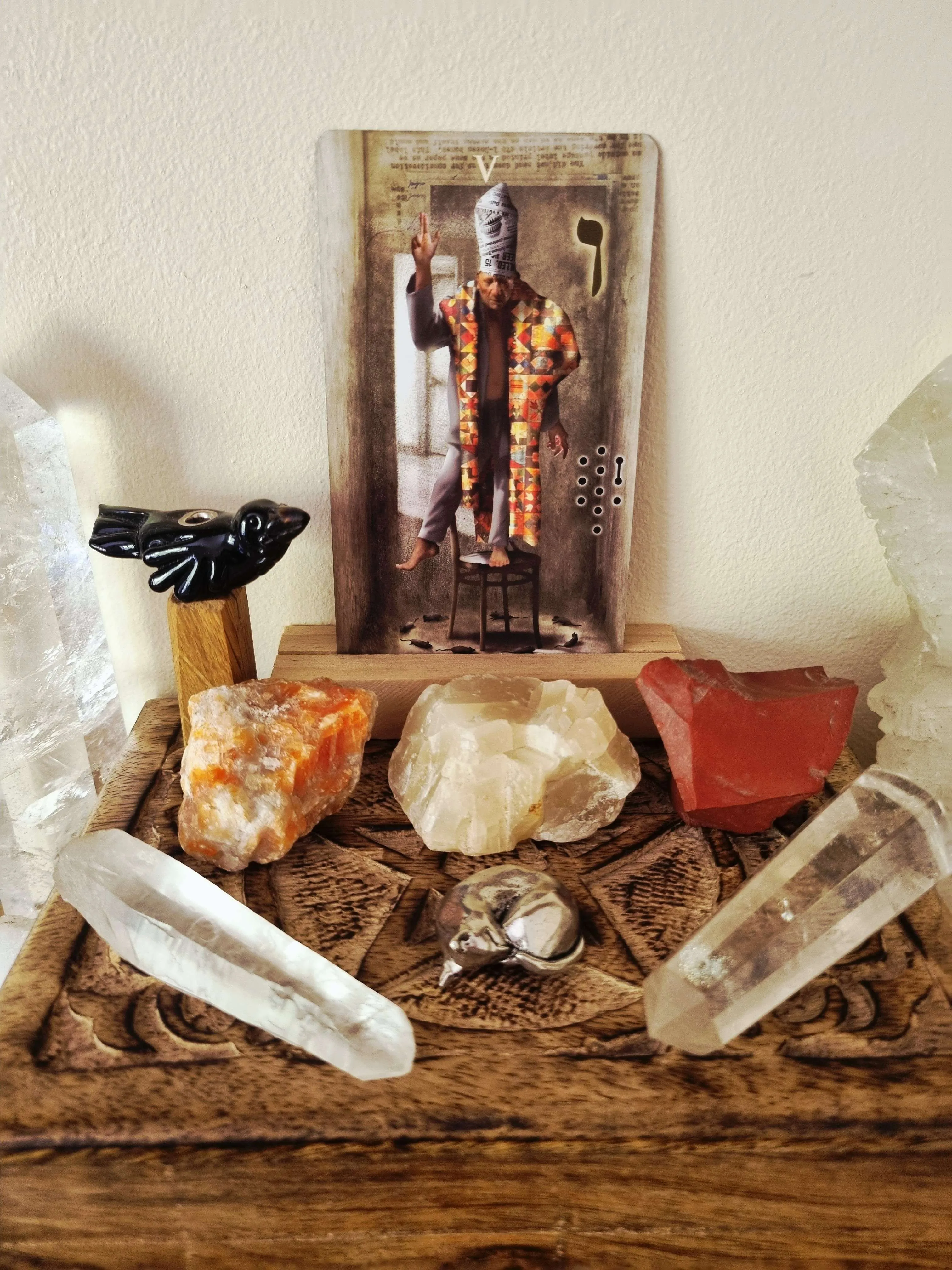 tarot card on a home altar surrounded by raw crystals and a black bird figurine