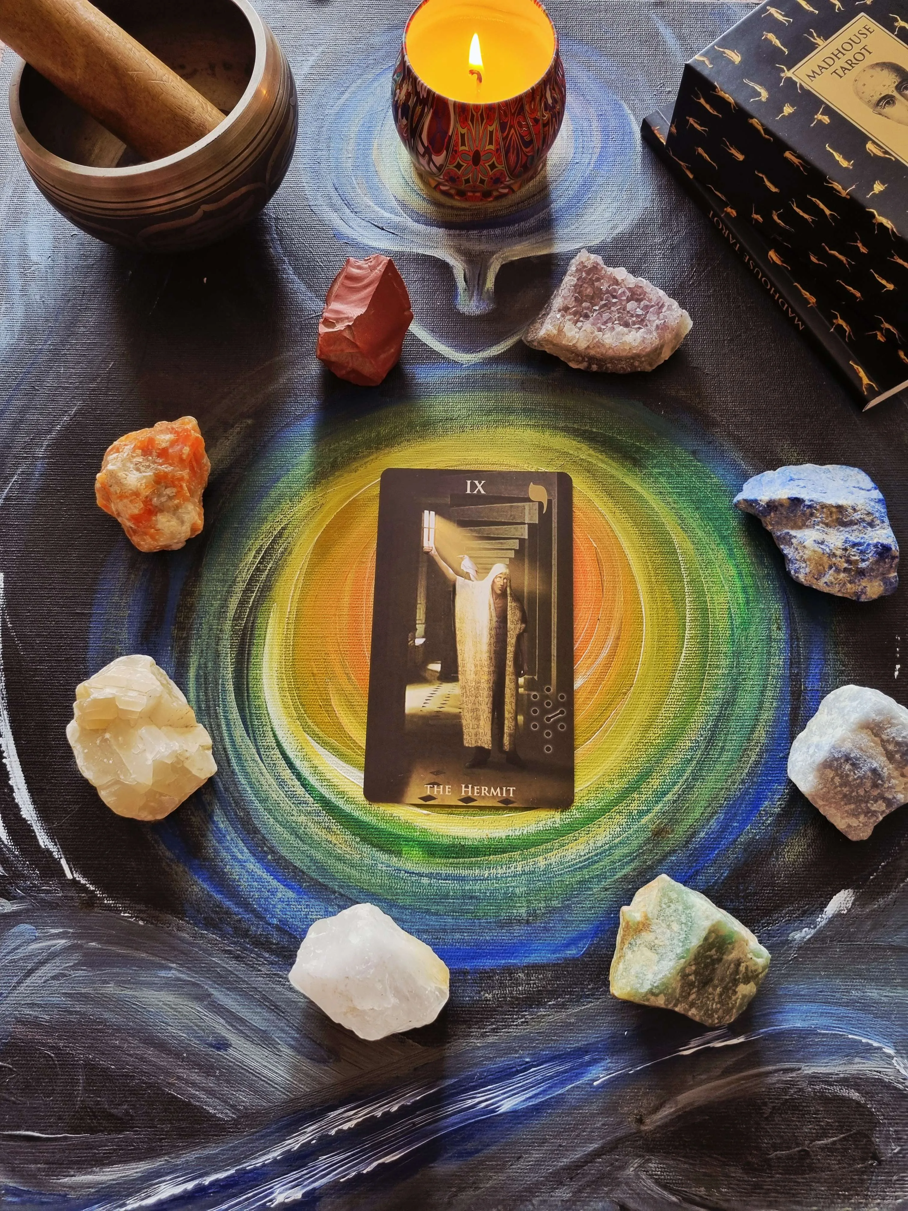 The Hermit tarot card on an altar cloth with a candle and singing bowl for meditation