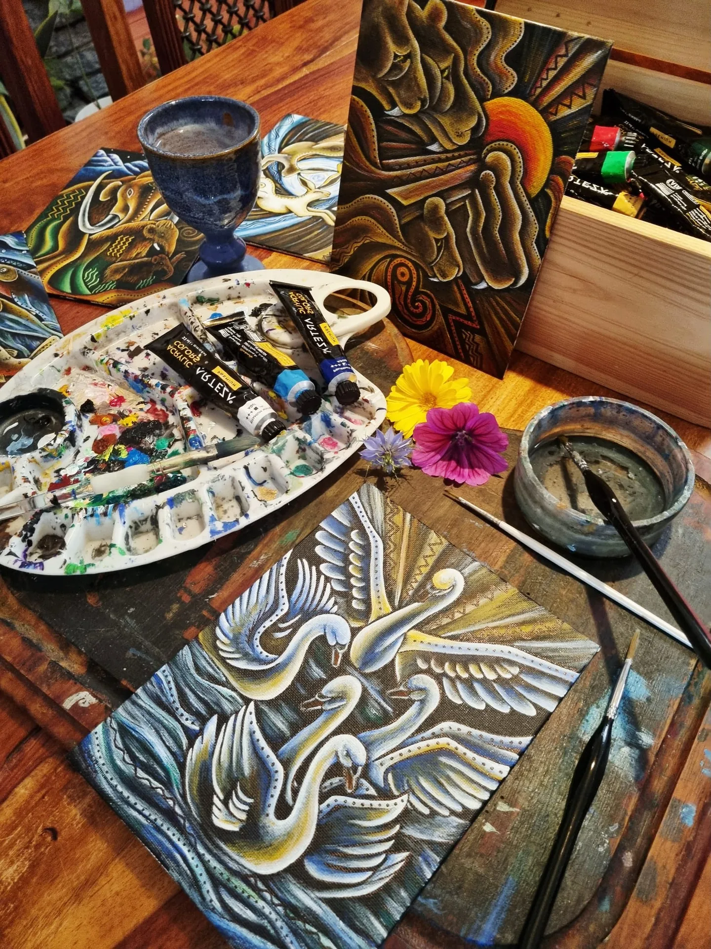 hand painted tarot cards drying on an artist's studio desk with paint palette and fresh flowers