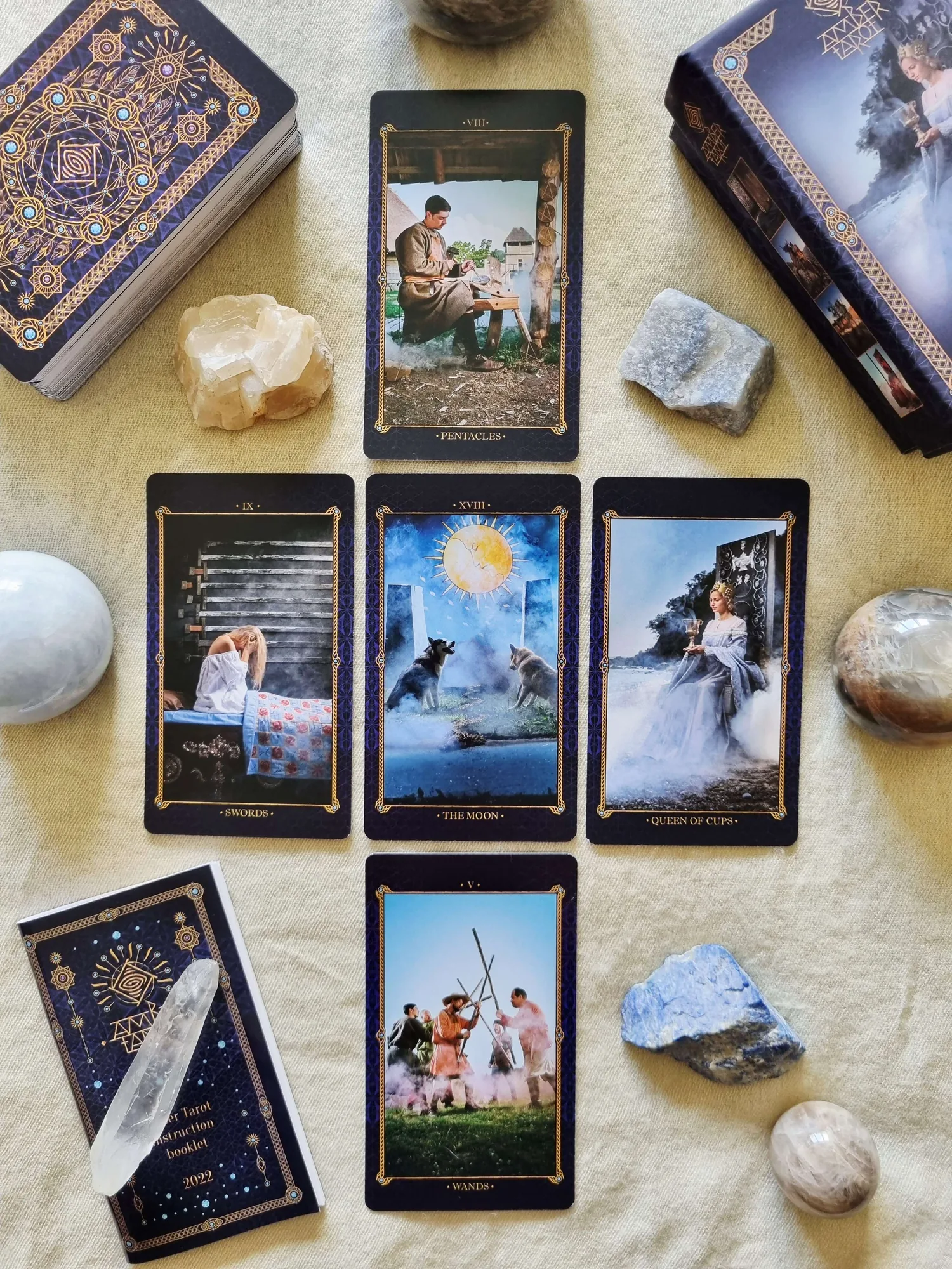 Amber Tarot cards including The Moon and the Queen of Cups laid out beside the deck, the instruction booklet and a clear quartz crystal