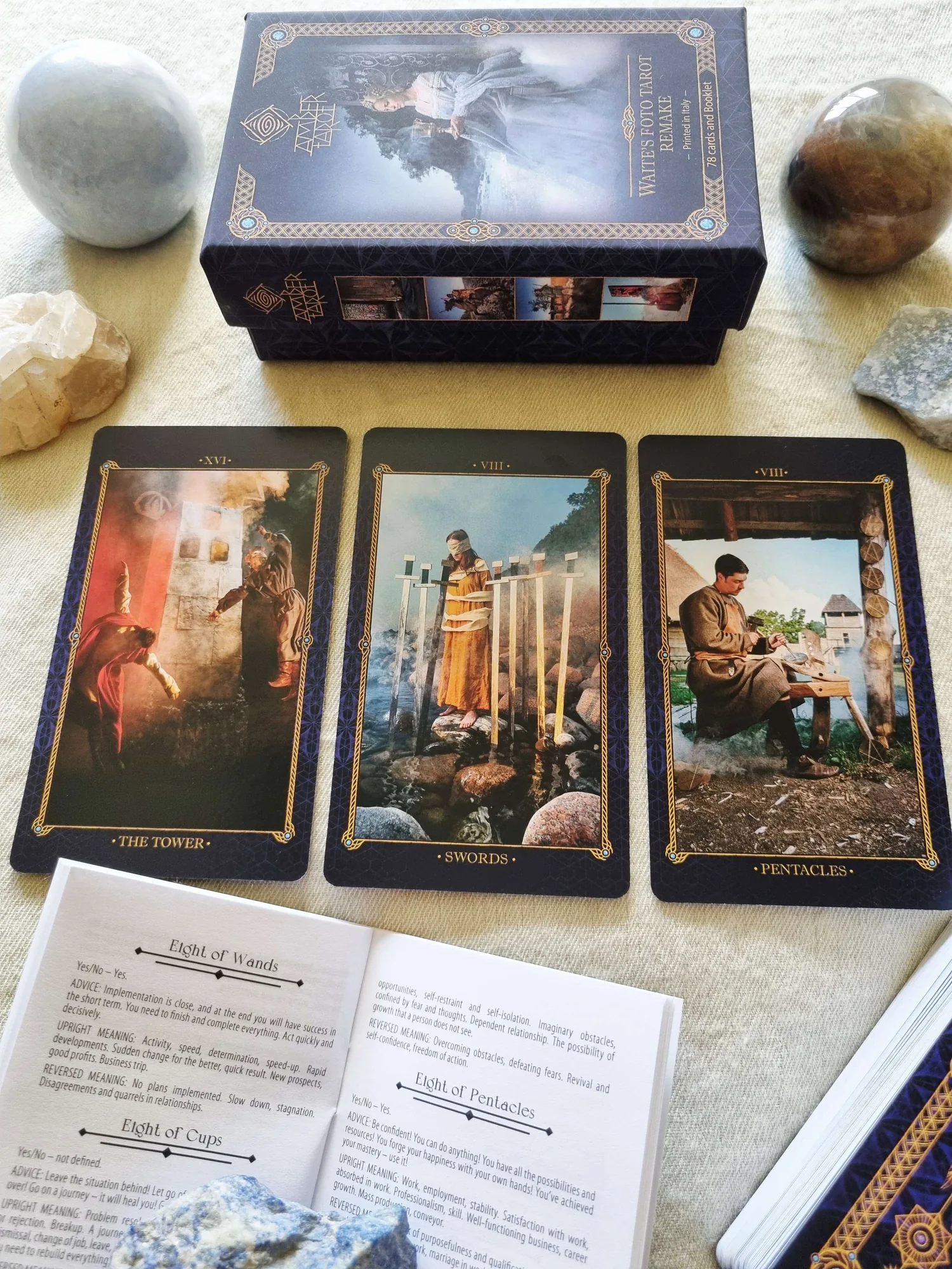 Amber Tarot box above The Tower and two Minor Arcana cards, with the printed booklet open beside them