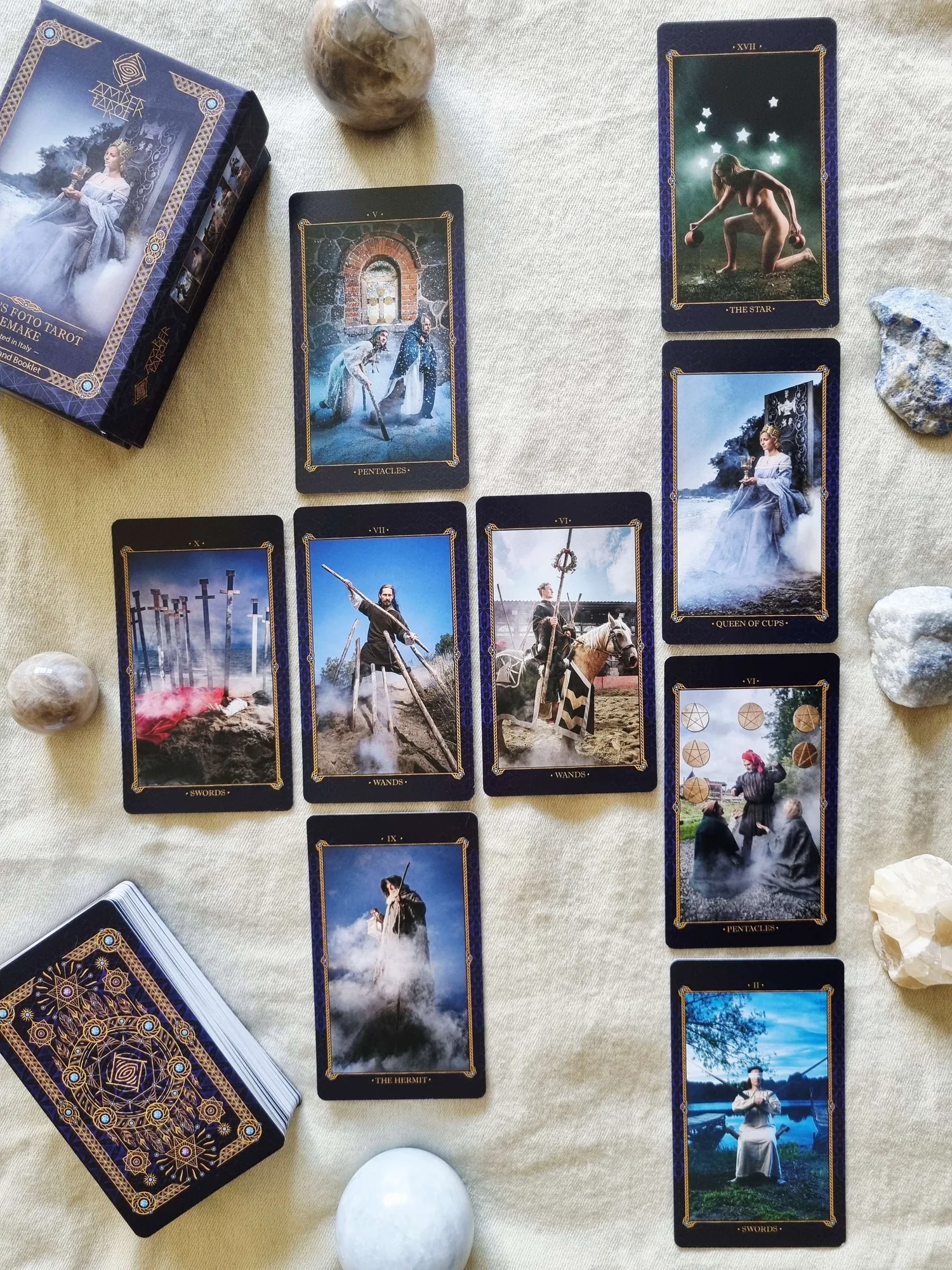 Amber Tarot cards including The Star and the Queen of Cups in a cross-shaped layout beside the deck box and stone spheres