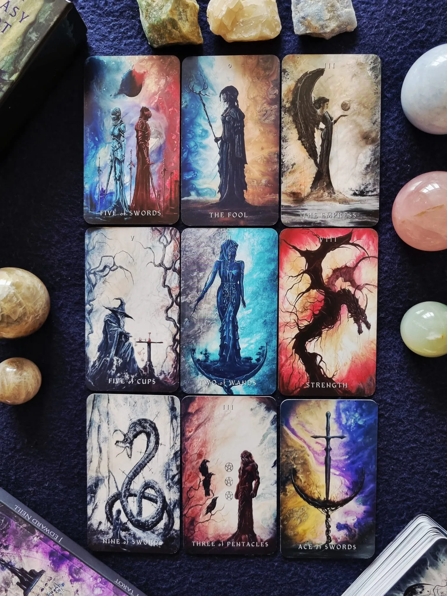 Nine Dark Fantasy Tarot cards in a grid including the Five of Swords, The Fool, The Empress, Strength and the Ace of Swords, surrounded by polished crystal spheres.