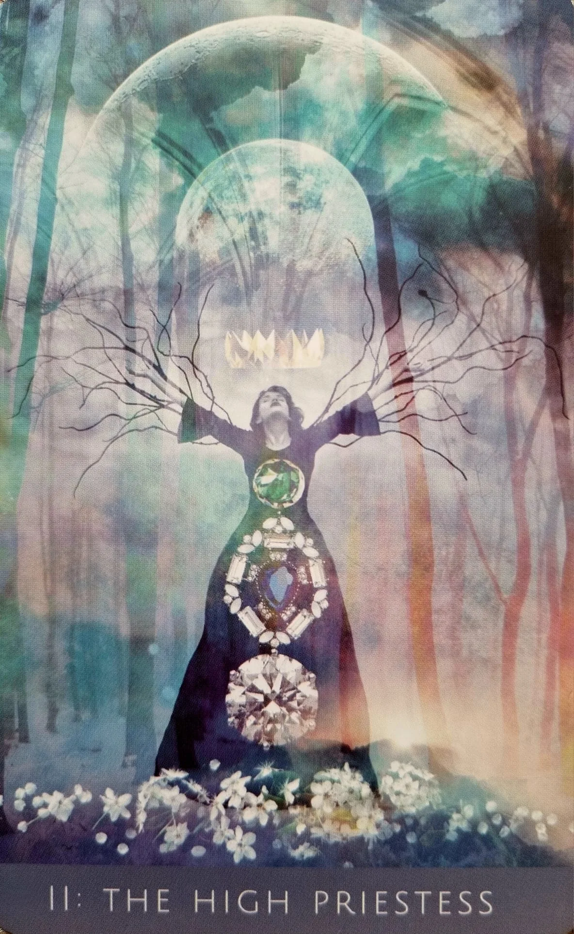 The High Priestess card from the Rooted Remembrance Tarot, a figure with branch-like arms outstretched in a misty forest, crowned in light