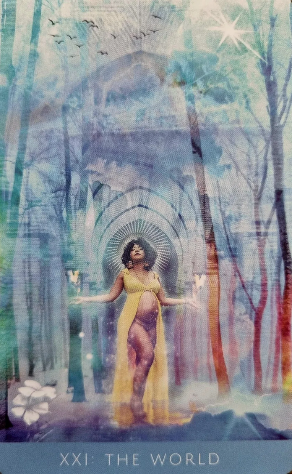 The World from the Rooted Remembrance Tarot, a figure in yellow standing with arms open beneath a woodland archway