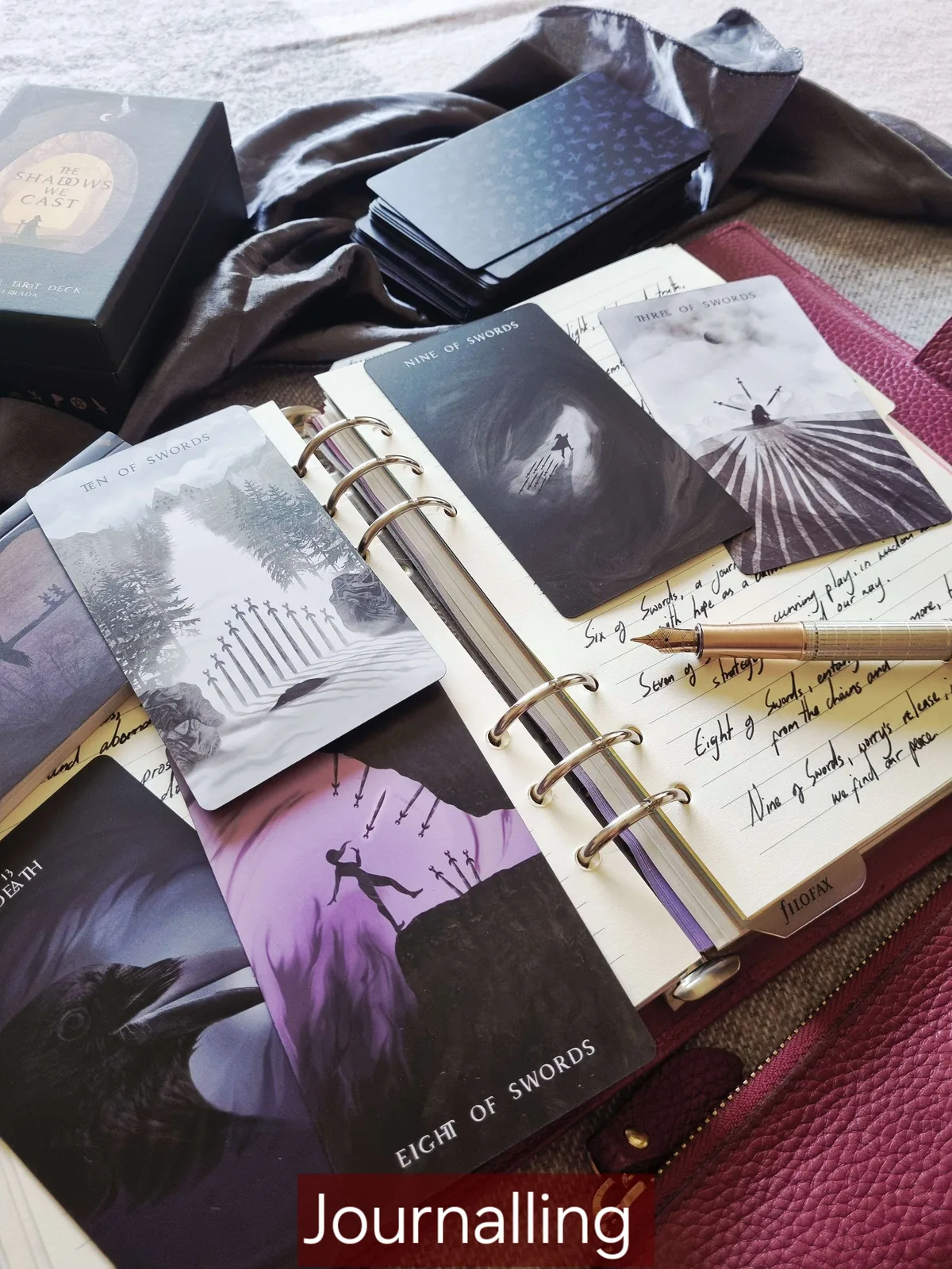 The Shadows We Cast Nine and Ten of Swords cards on an open tarot journal for shadow work journalling
