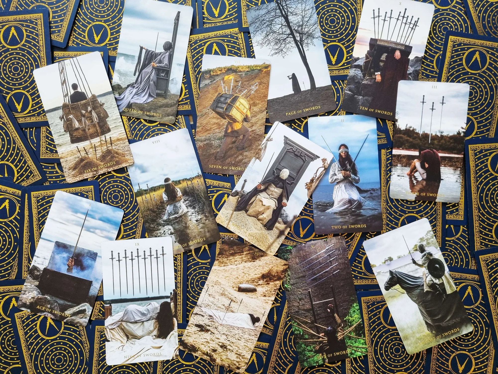 Somnia Tarot sword cards scattered across a table of blue and gold card backs