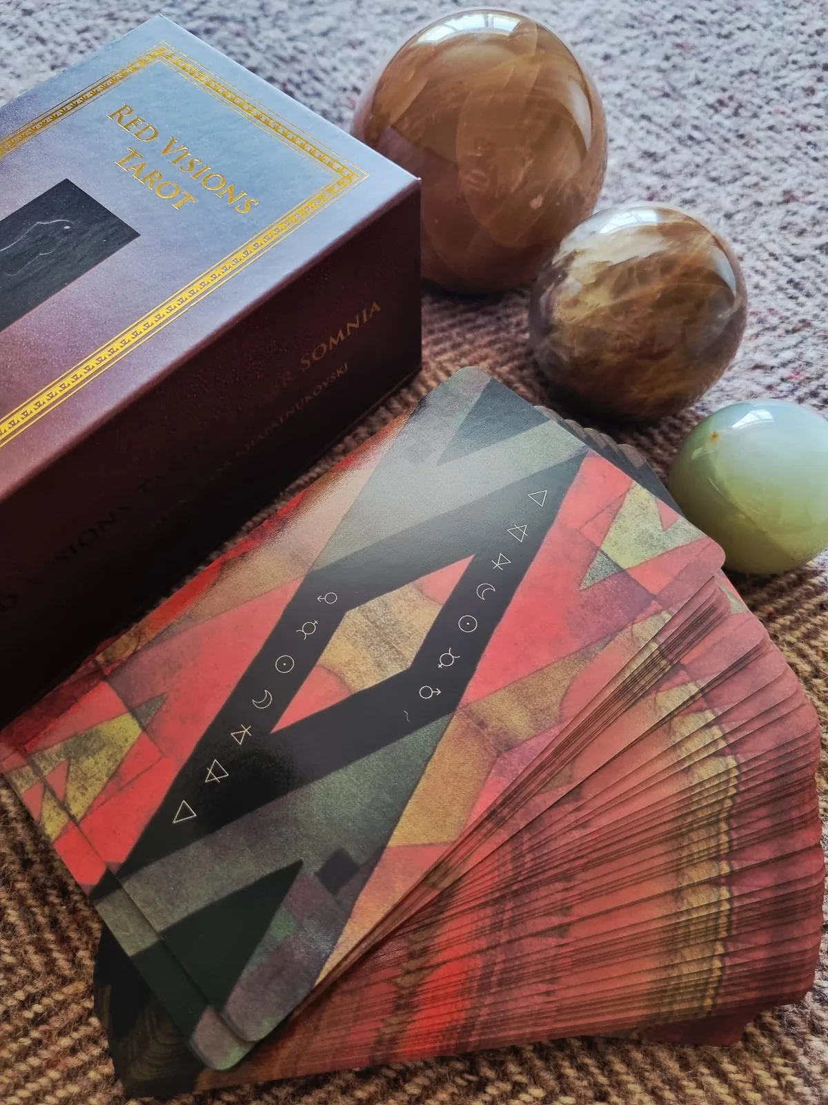 The red and black geometric card backs of Liber Somnia Red Visions Tarot with the gold gilded deck edge