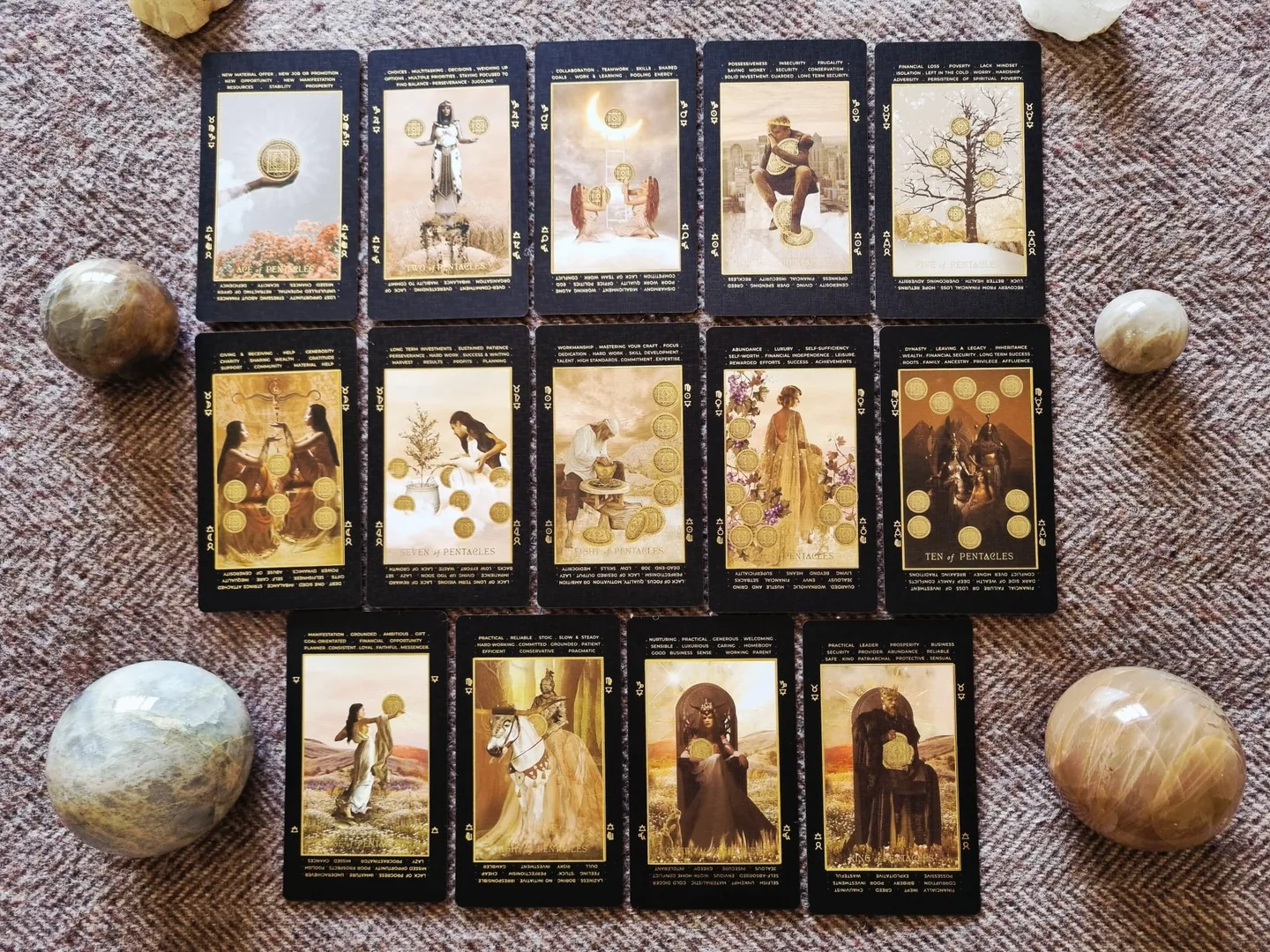 The complete suit of Pentacles from the Lucid Dreams Tarot, fourteen cards laid out in rows with crystal spheres