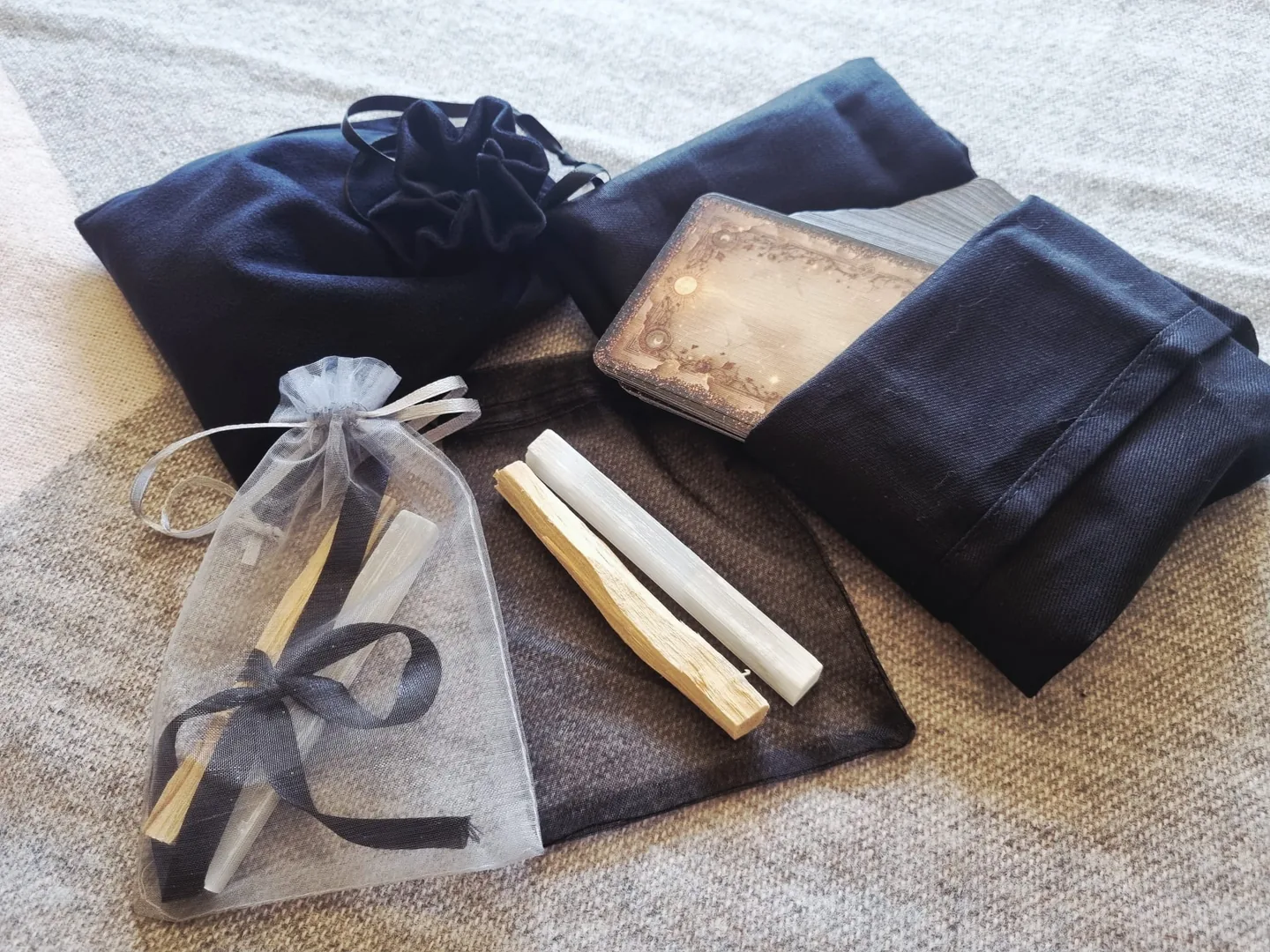 A velvet tarot bag, a tarot cloth, a deck of cards and an organza pouch holding Palo Santo and Selenite sticks