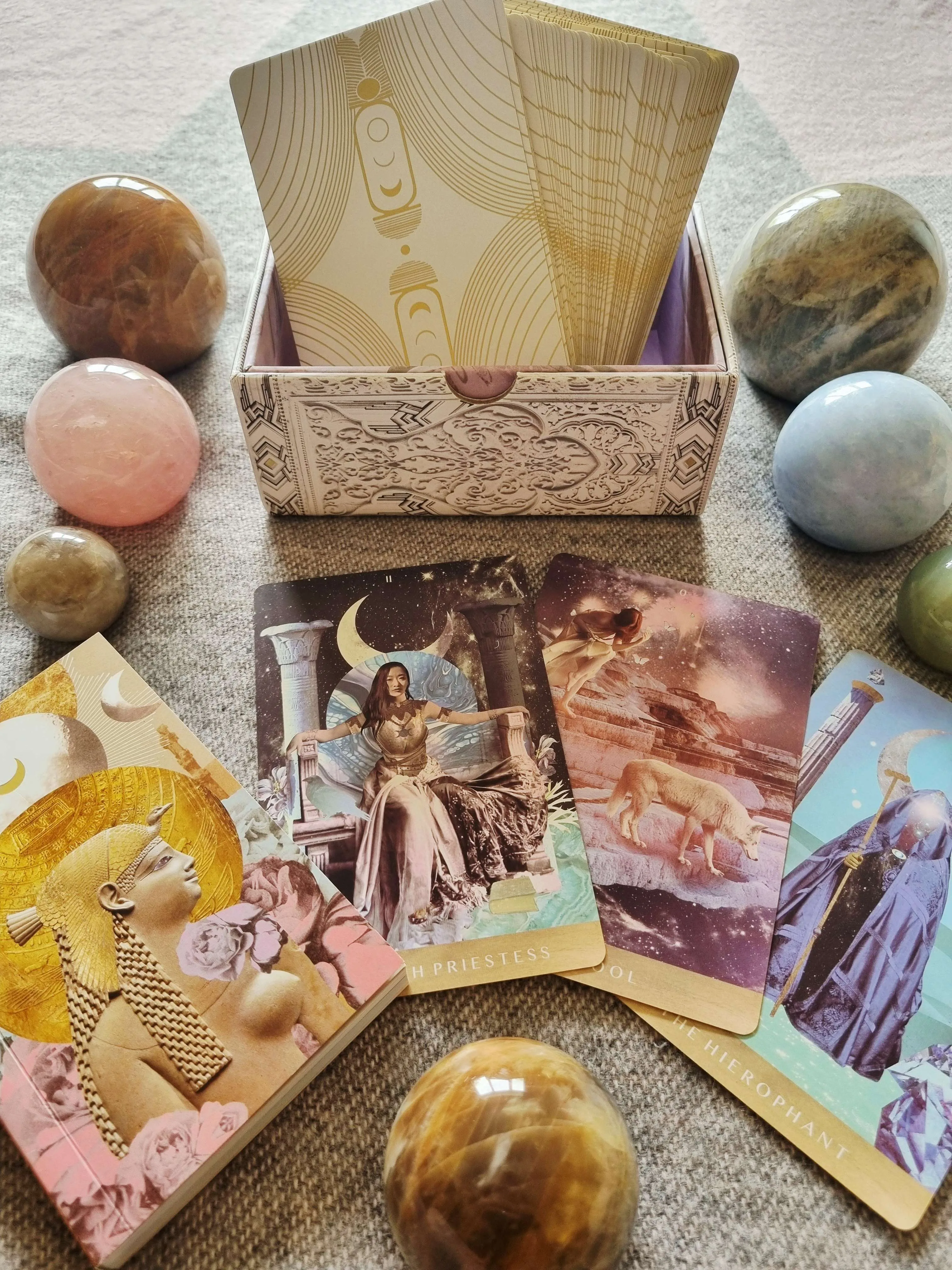 the Moonchild Tarot White and Gold Edition box open with the deck fanned out beside The High Priestess, The Fool and The Hierophant cards