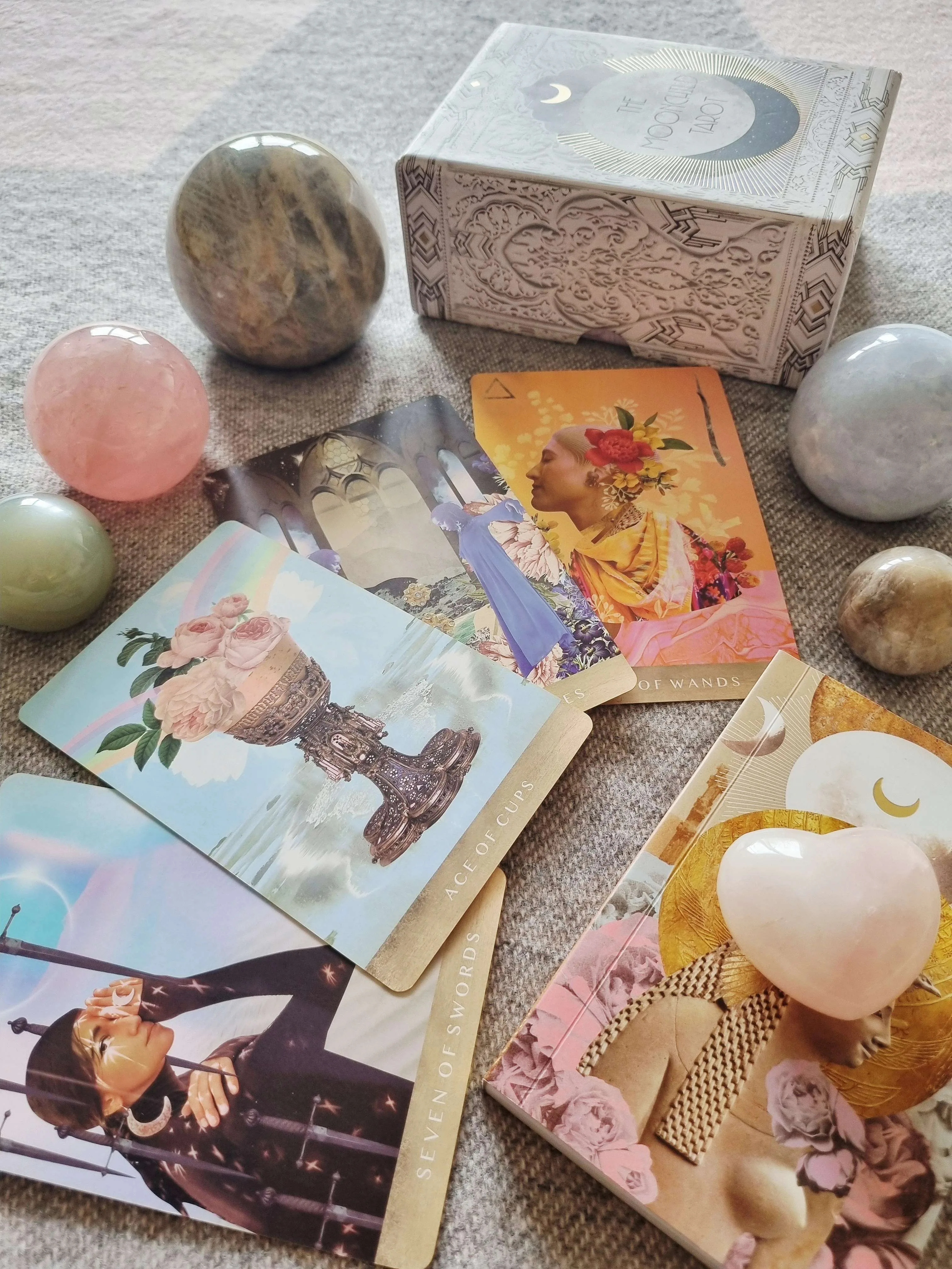 The Moonchild Tarot White and Gold Edition box beside the Ace of Cups, Seven of Swords and Six of Wands cards