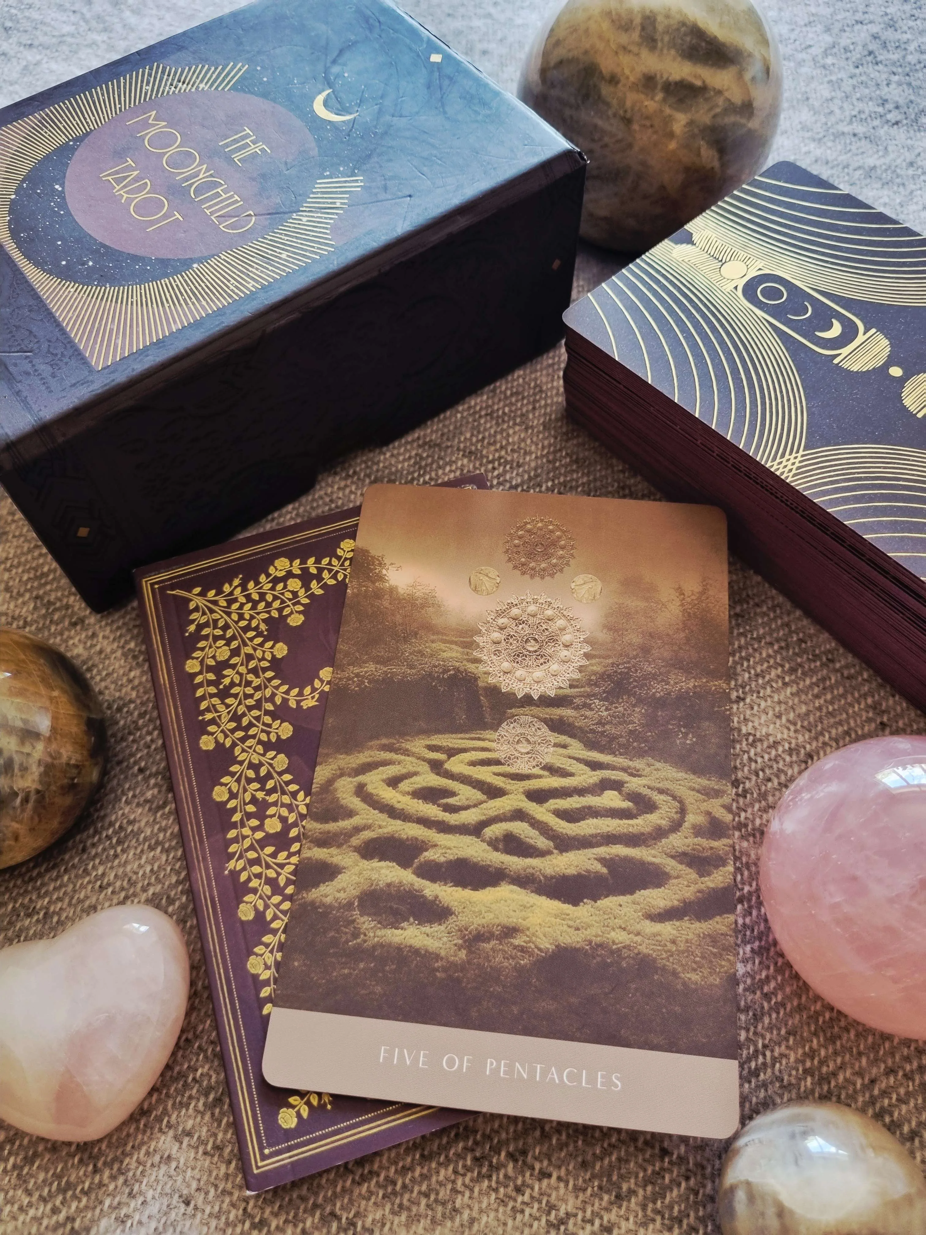 The Moonchild Tarot Shadow Work Edition box beside The Five of Pentacles card and the deck fanned out