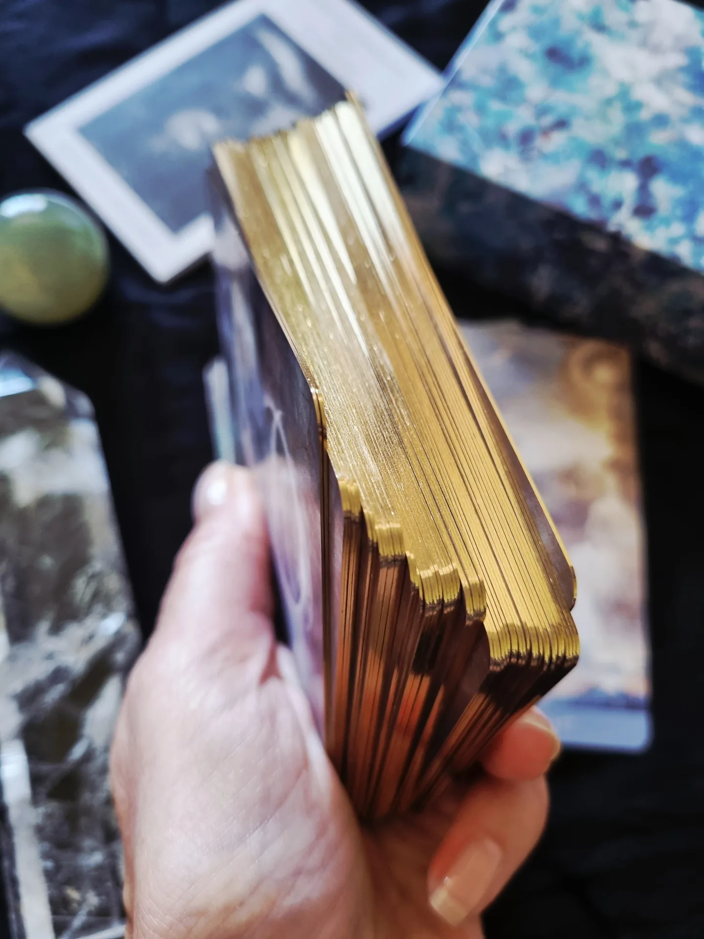 Close-up of the Rooted Remembrance Tarot gold gilded card edges held in hand