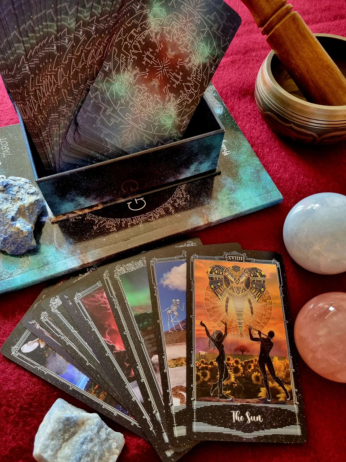 Cosmosis Tarot deck in its box with fanned cards and The Sun beside a singing bowl