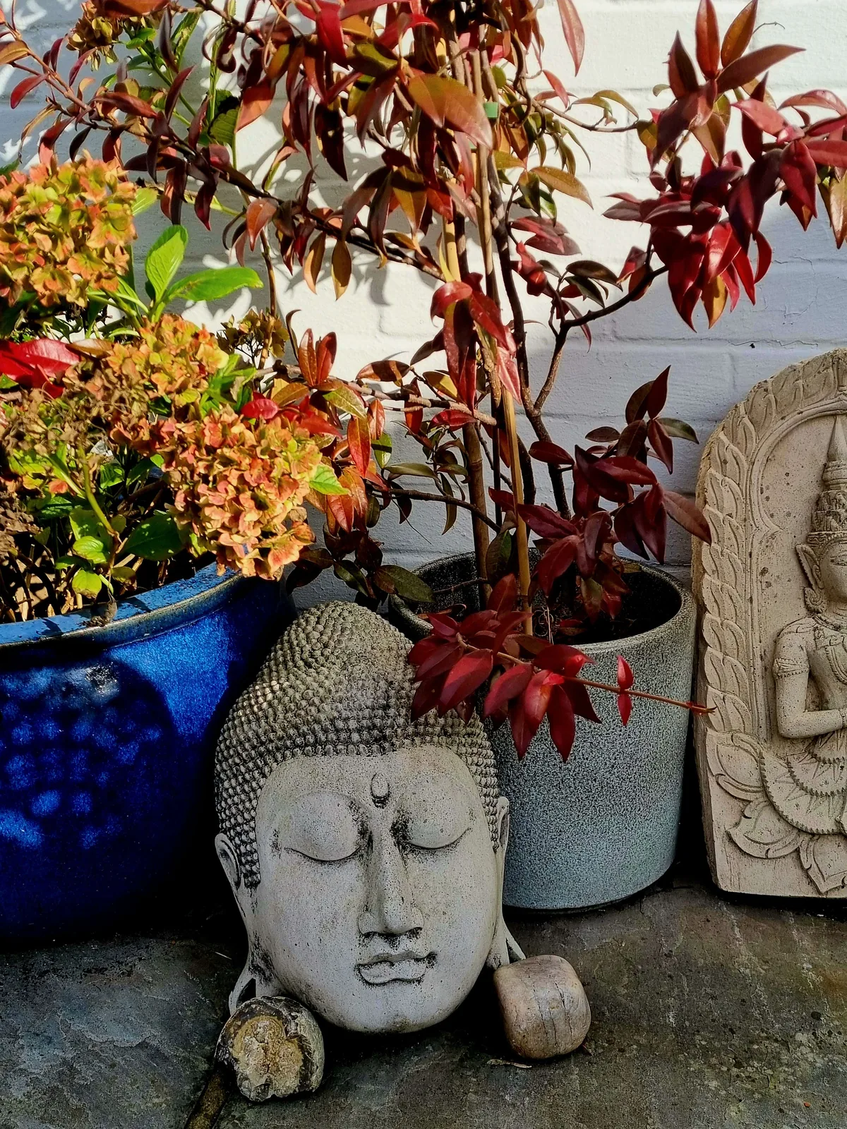 stone Buddha head among autumn leaves for an ancestral remembrance space