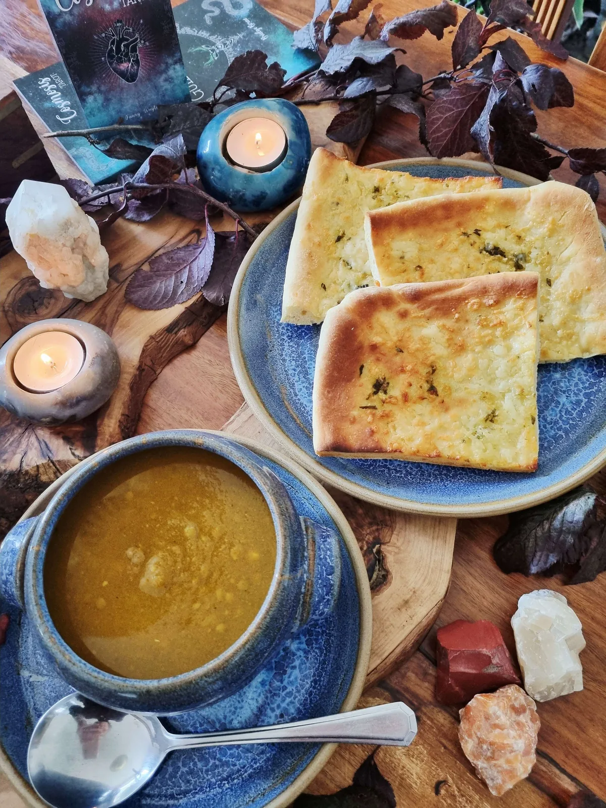 bowl of pumpkin and lentil soup with garlic flatbread, candles and crystals for Samhain