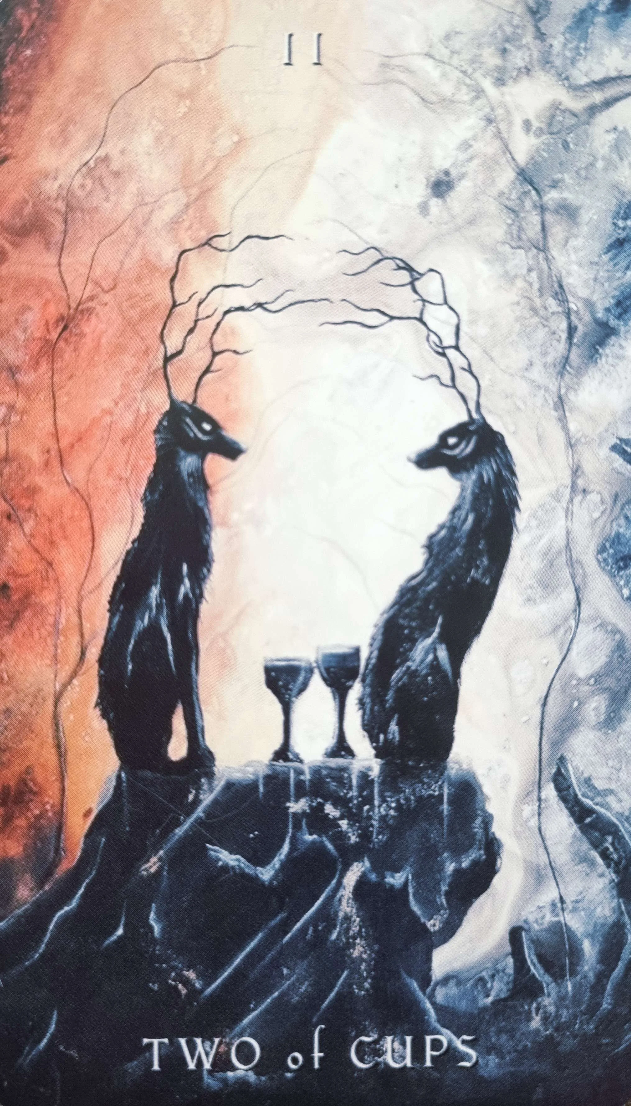 Two of Cups tarot card, two antlered figures facing each other over twin goblets