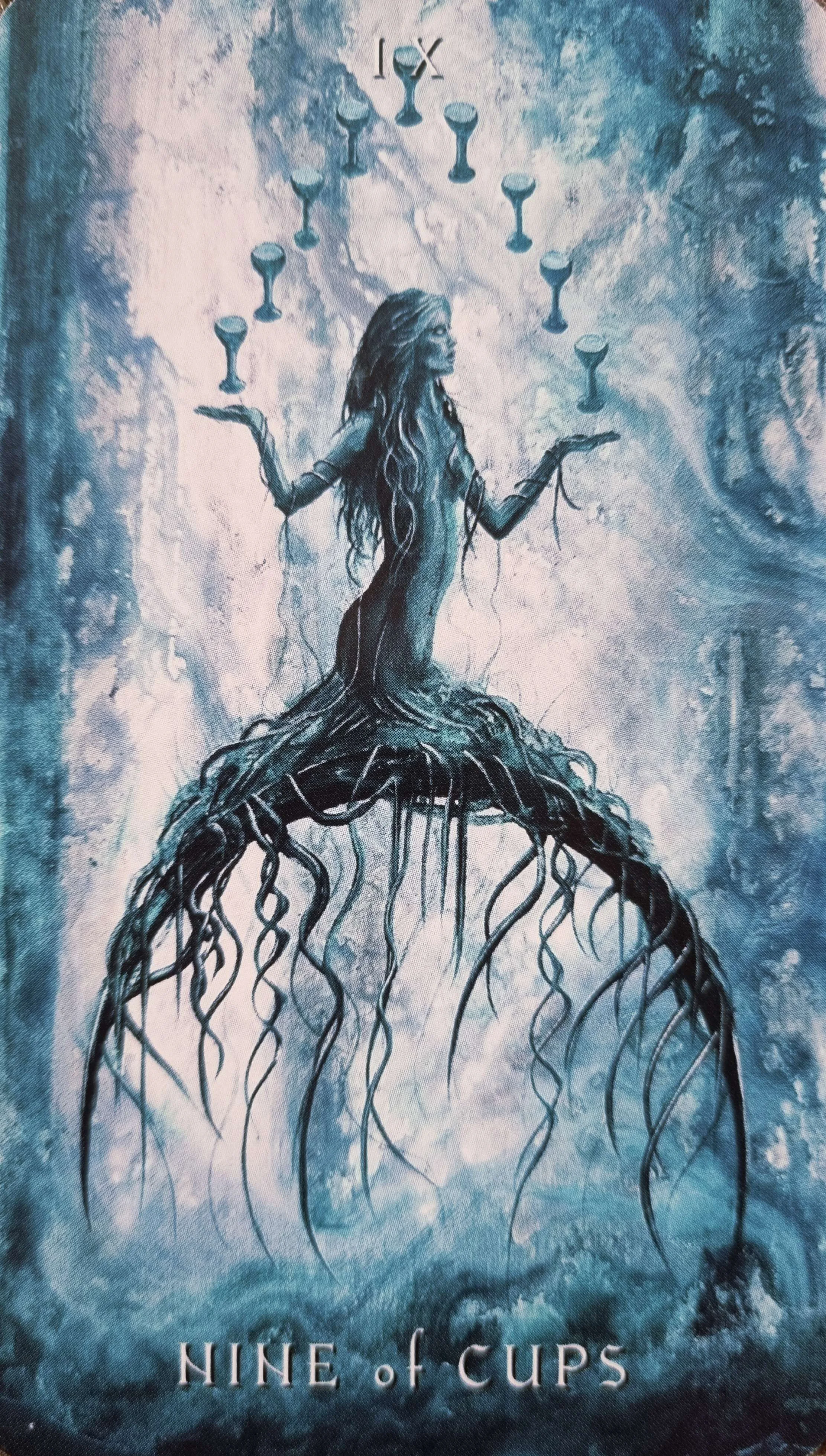 Nine of Cups tarot card, a wraithlike rooted figure holding cups aloft