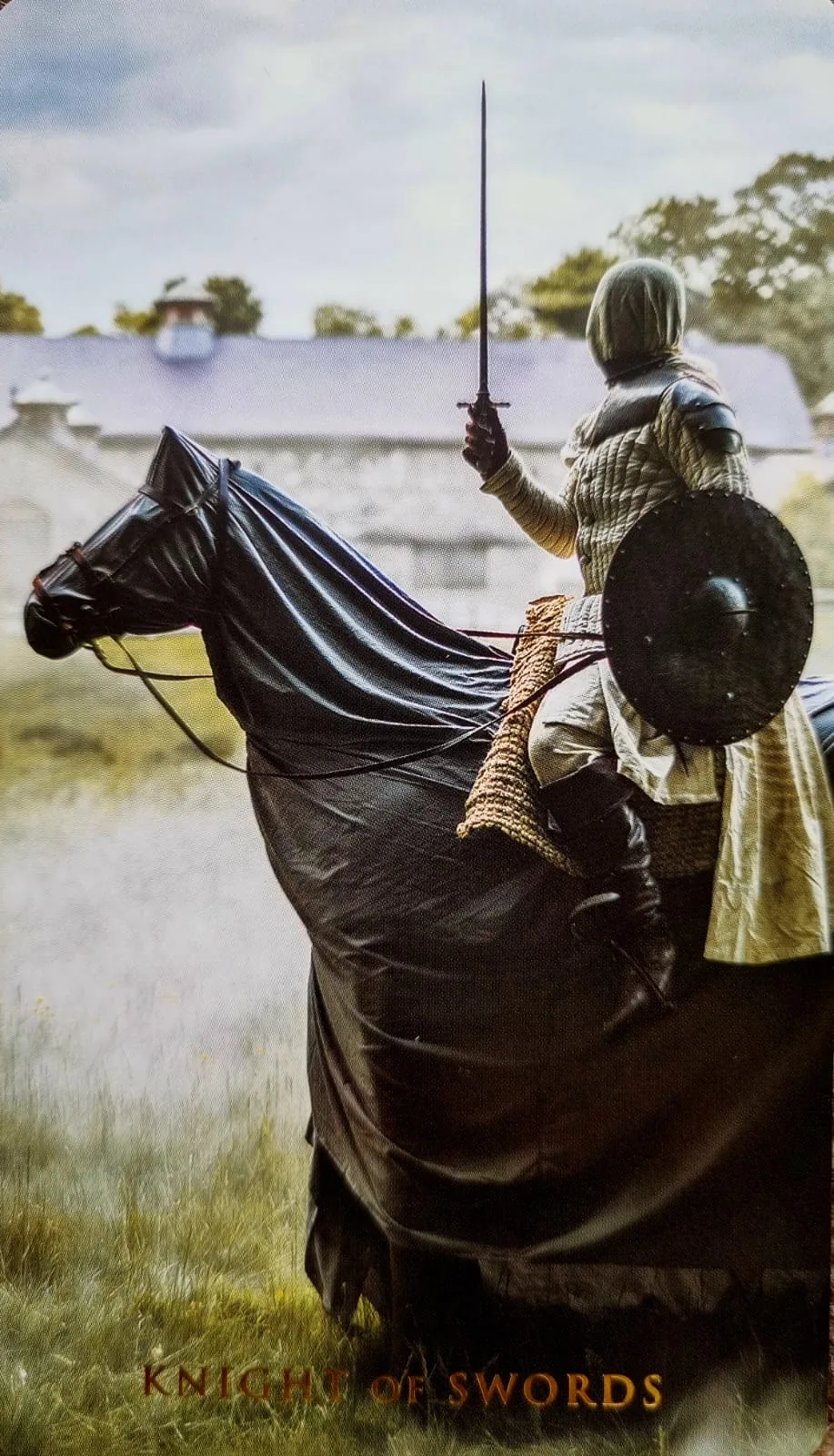 Knight of Swords card: an armoured rider on a dark horse raising a sword mid-charge