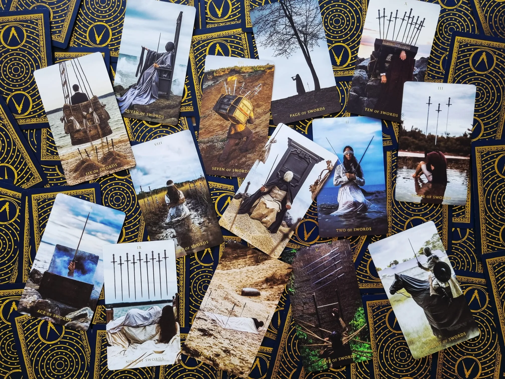 The fourteen Suit of Swords cards scattered across the gold-patterned card backs