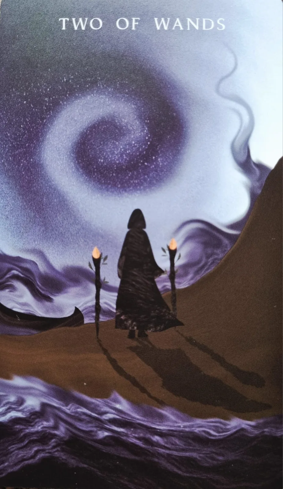 Two of Wands tarot card, a cloaked figure with two torches beneath a spiral of stars