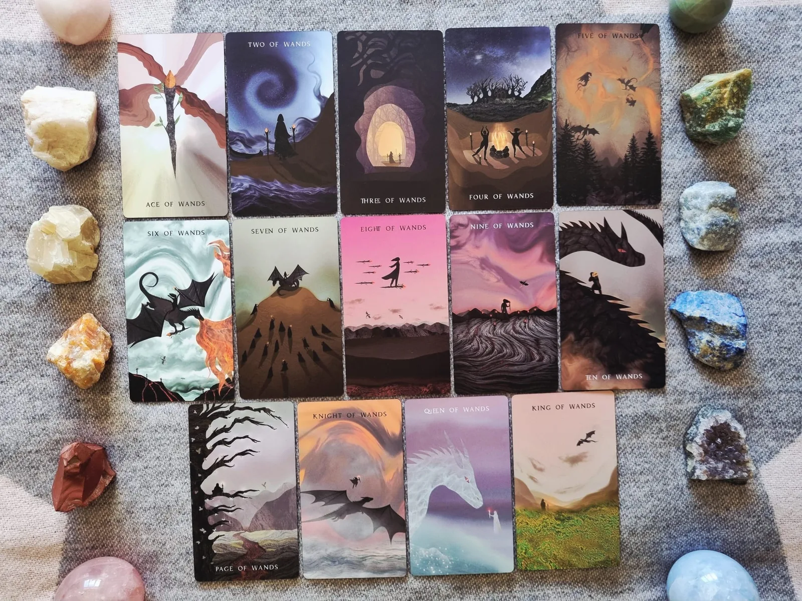 Full Suit of Wands from The Shadows We Cast tarot laid out with crystals