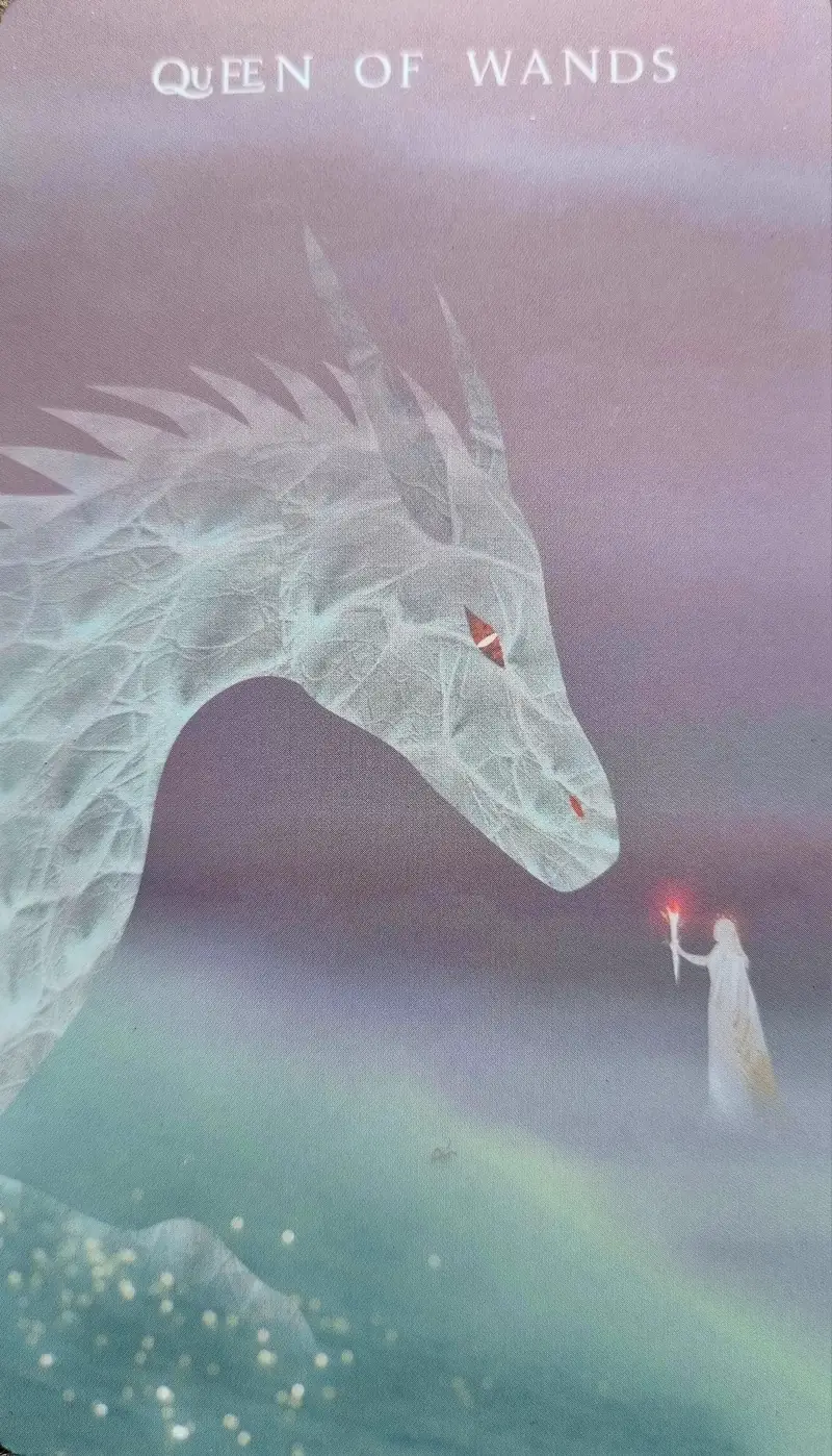 Queen of Wands tarot card, a robed figure holding a flame before a great white dragon