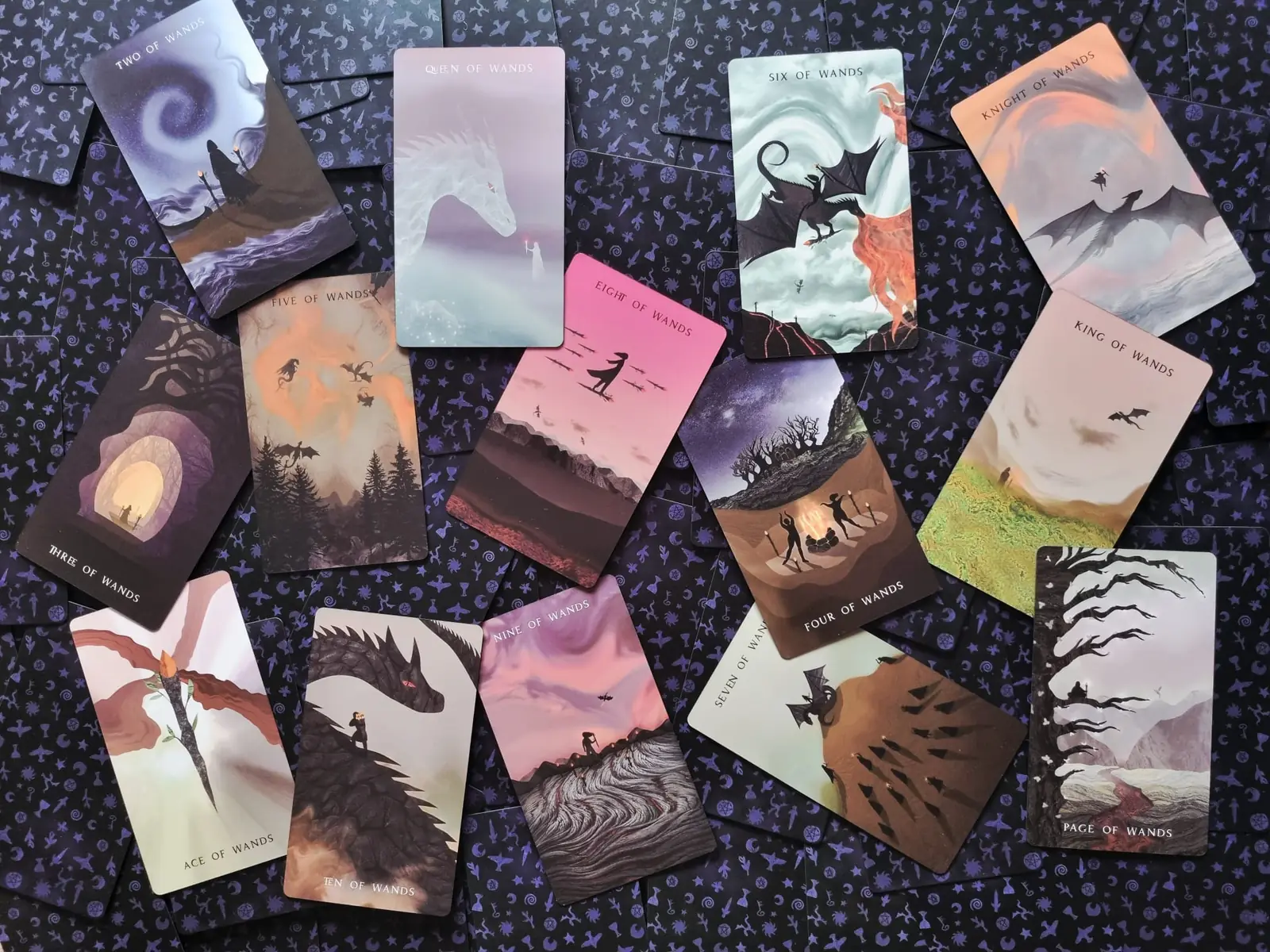 Suit of Wands tarot cards scattered across a deep purple star patterned cloth