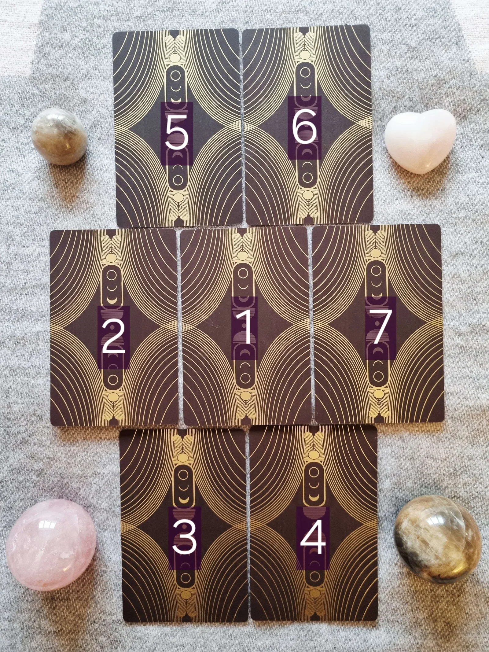 Seven card Meet Your Protector tarot spread laid out face down with numbered positions, surrounded by crystals