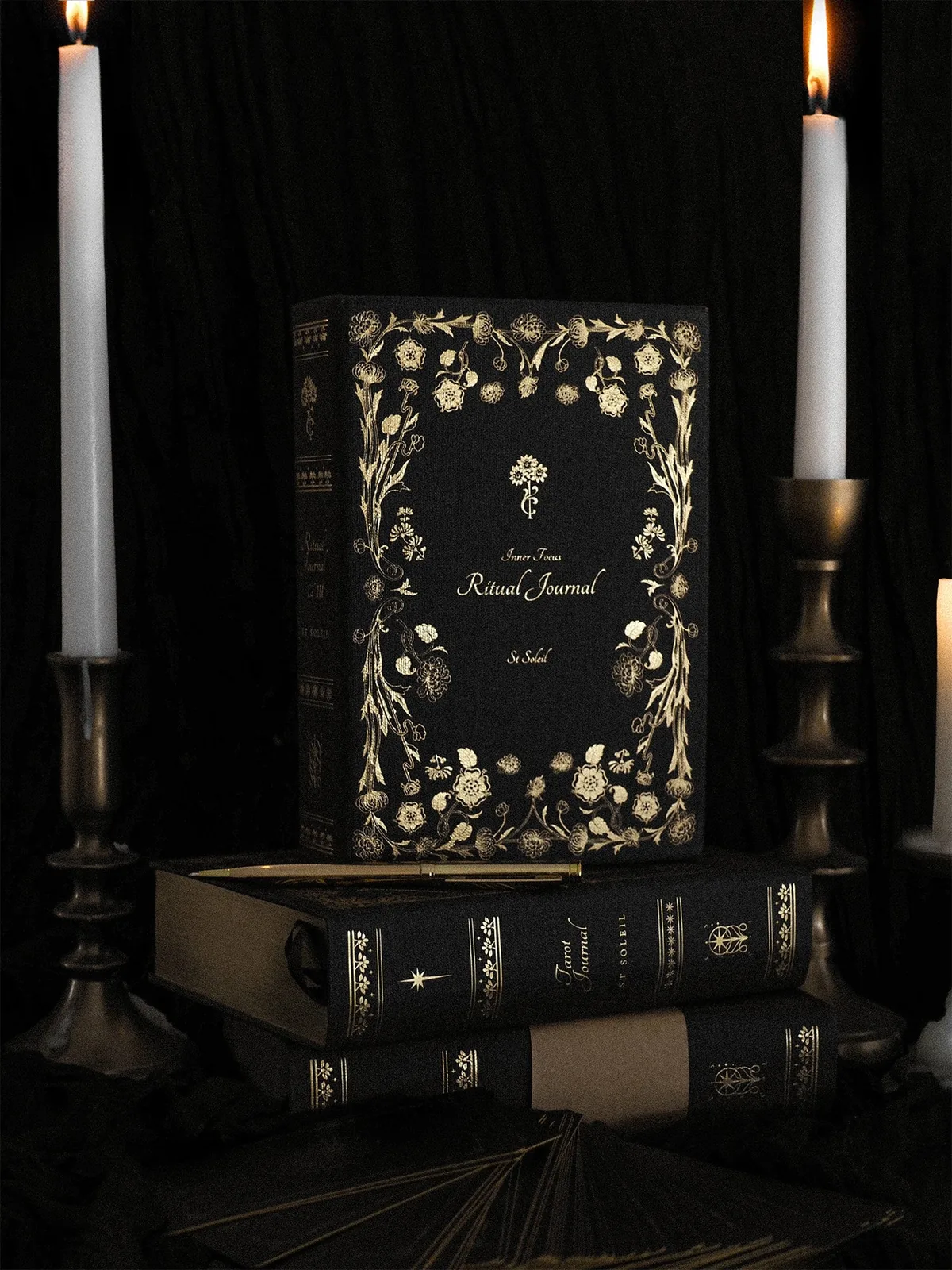 St Soleil Inner Focus Ritual Journal in black linen with gold floral foil, between two candles
