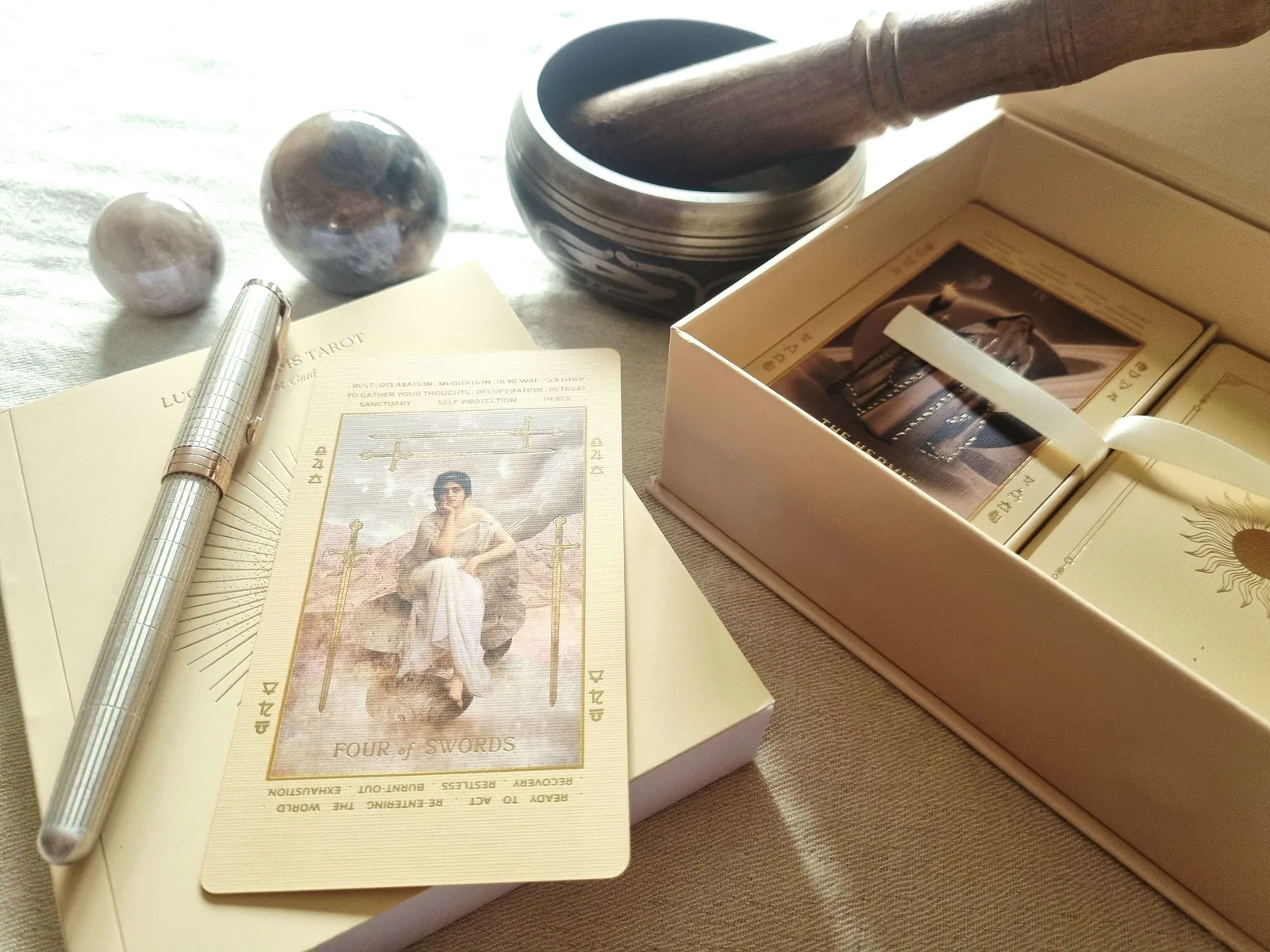 Four of Swords tarot card with a singing bowl, crystals and a fountain pen
