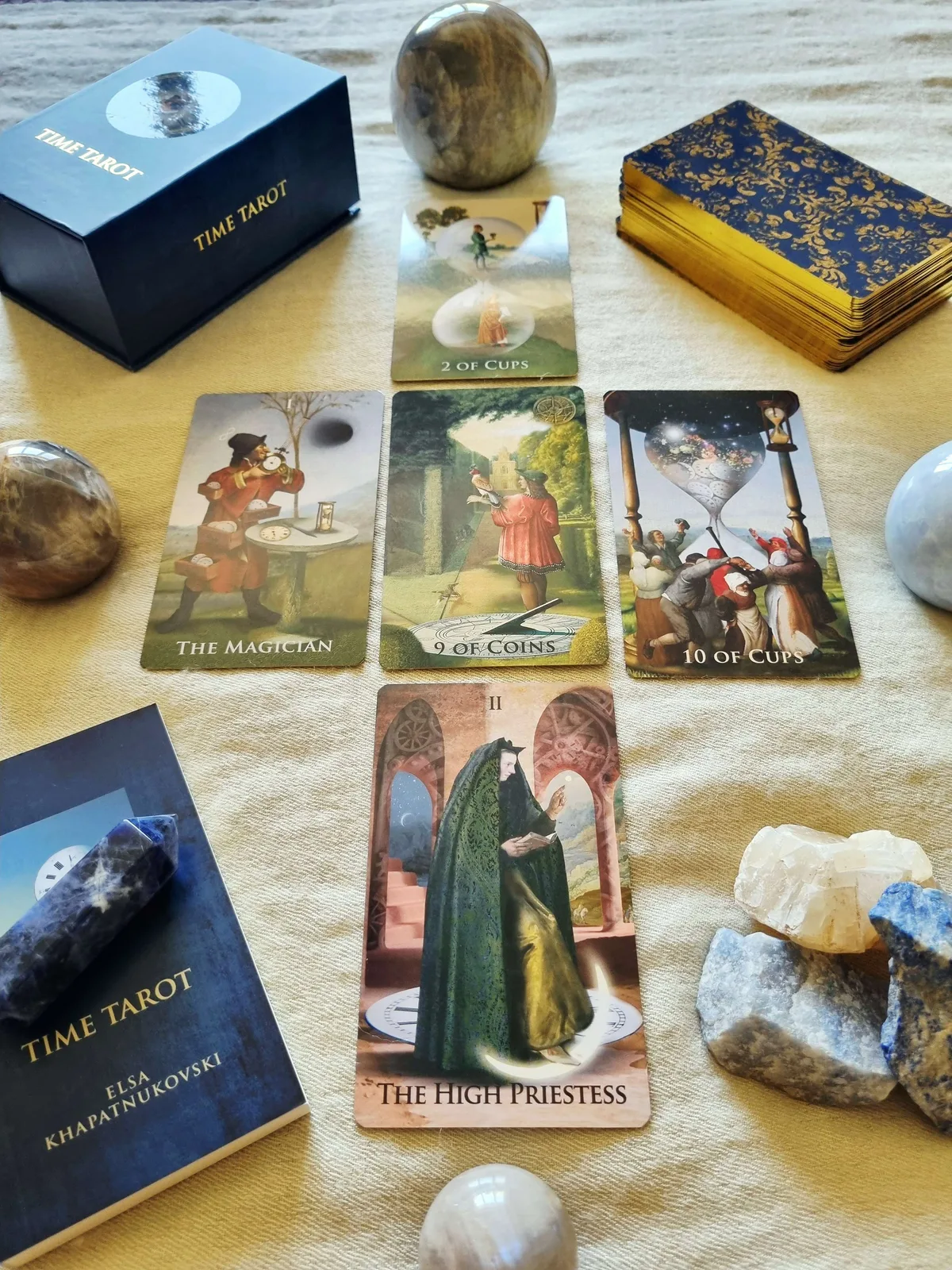 Time Tarot Magician, Nine of Coins, Ten of Cups and High Priestess cards beside the companion book