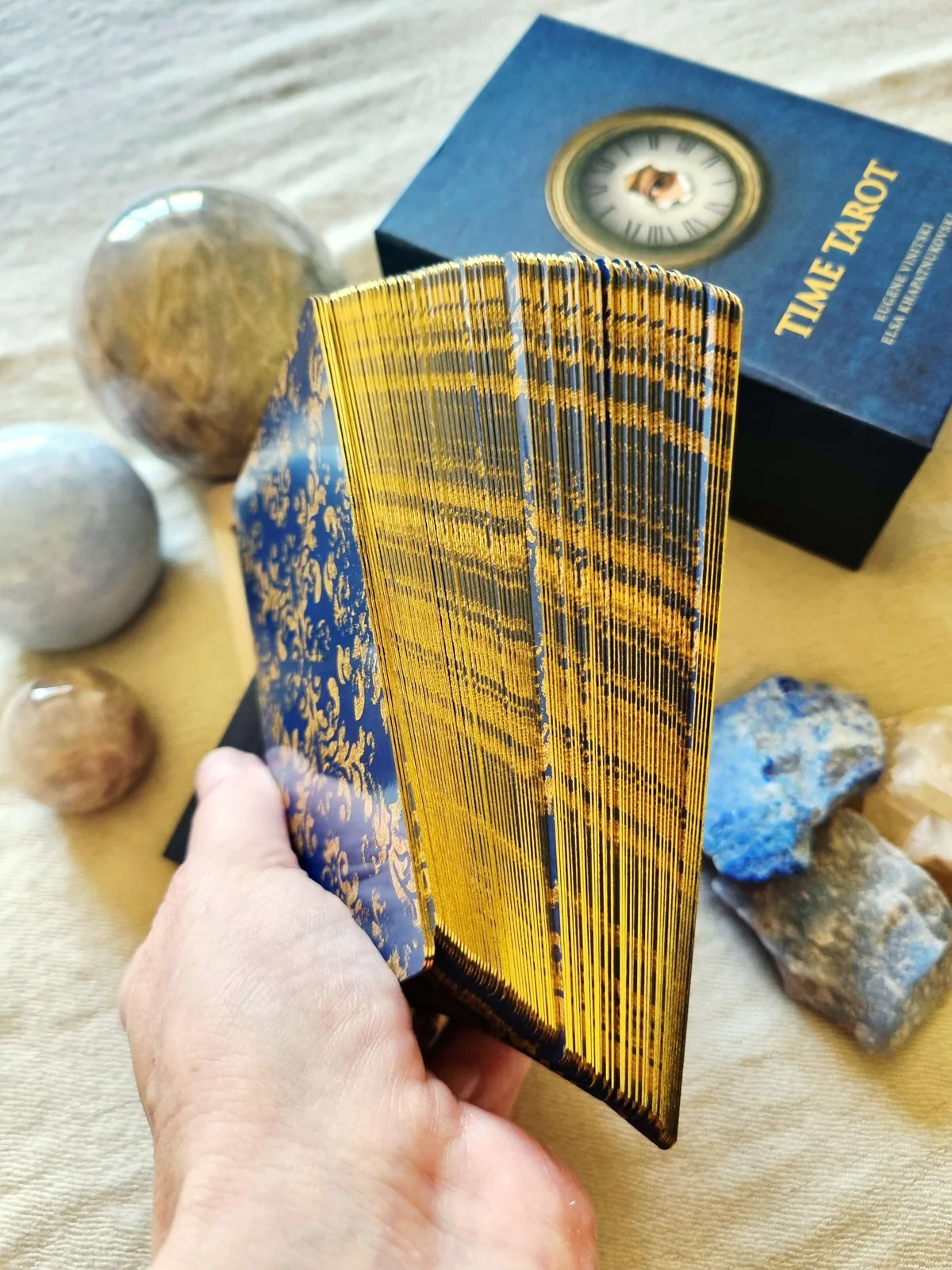 Gold gilded edges of the Time Tarot deck fanned in the hand