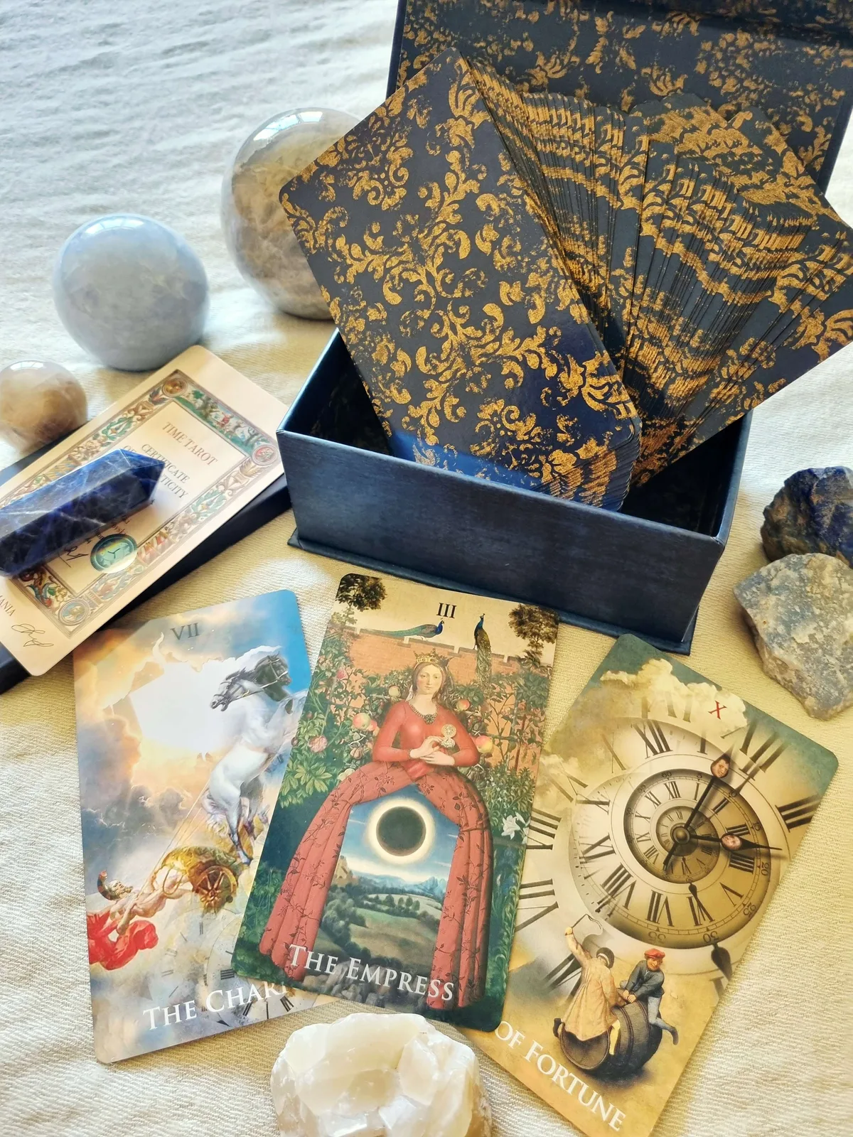 Open Time Tarot box with the blue and gold card backs and The Empress, Wheel of Fortune and Chariot cards