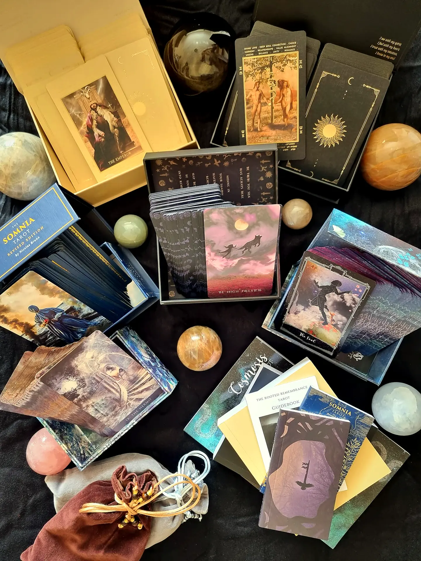 Independent tarot decks from The Guilded Veil, including Somnia, Cosmosis and Rooted Remembrance, with crystal spheres, guidebooks and handmade velvet pouches on dark velvet