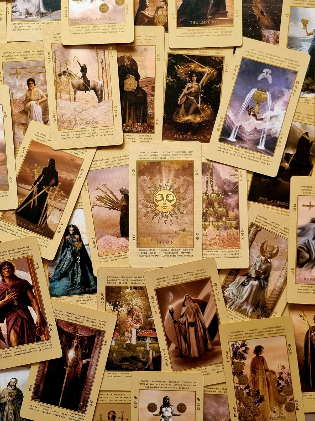 Overhead spread of dozens of gold bordered cards from the beige deck, including The Emperor and a sun faced card at centre