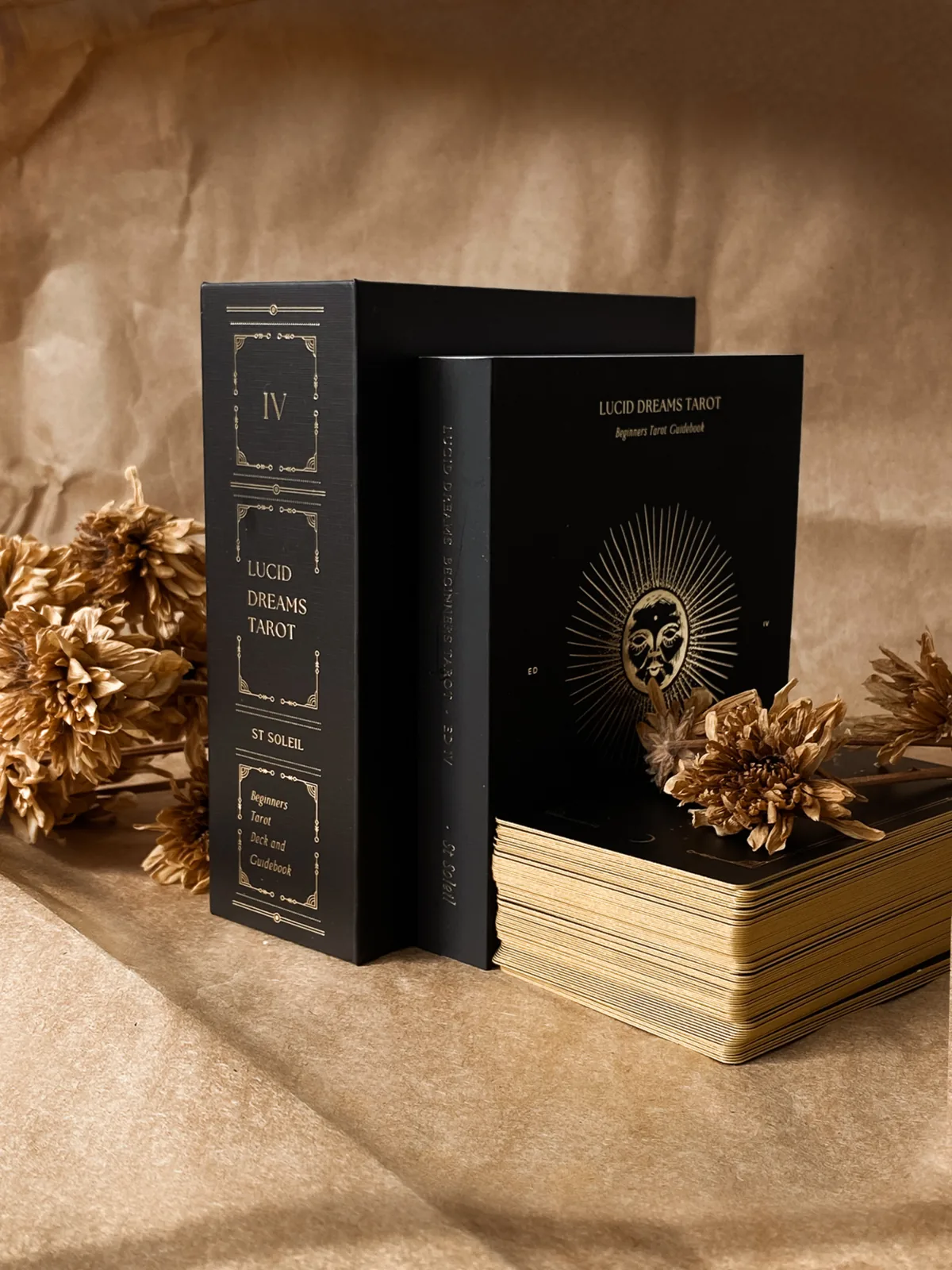 The Black Eclipse edition slipcase by ST SOLEIL stands beside its guidebook and gilded deck among dried flowers